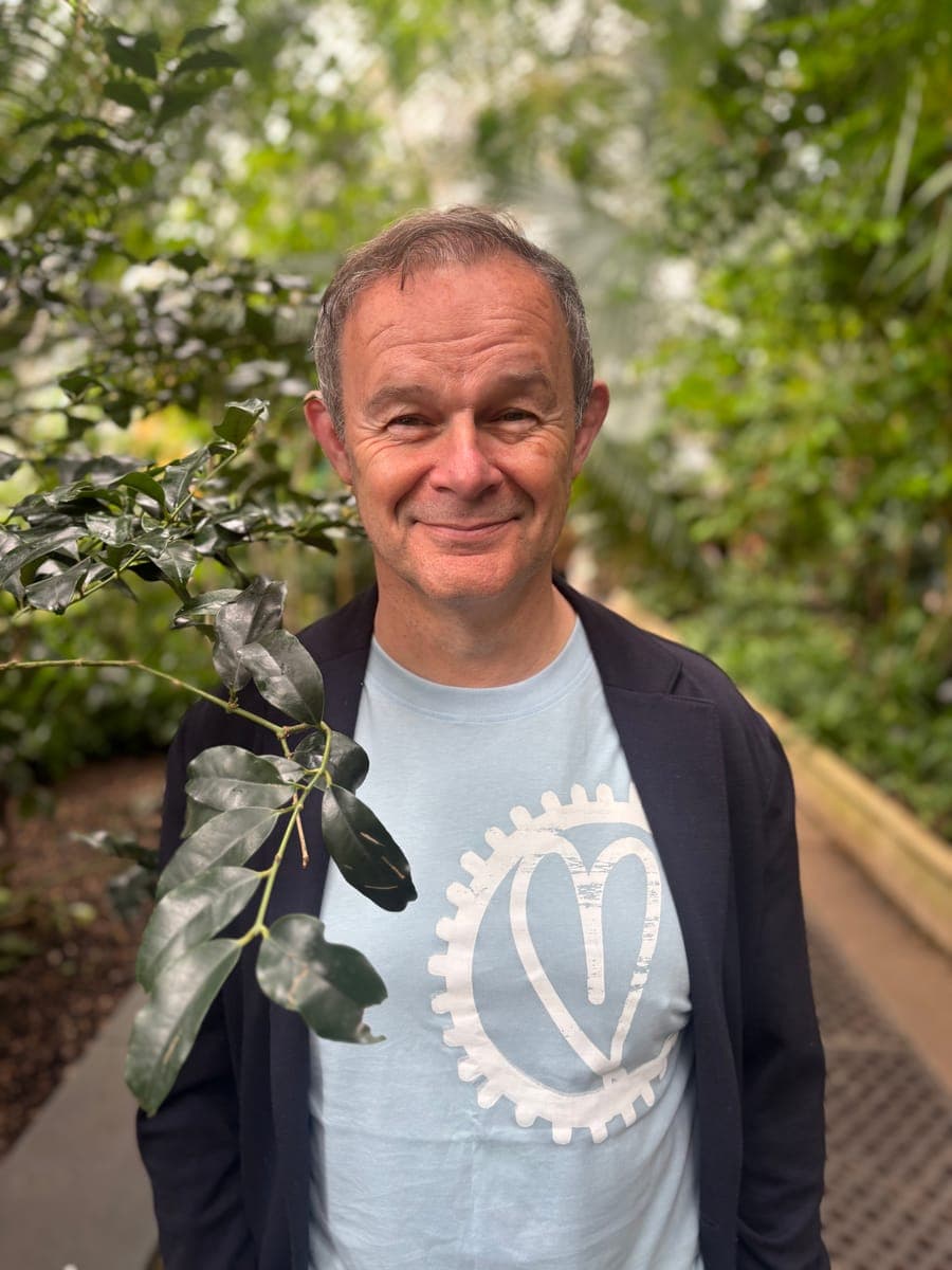 Andrew smiling among the plants in a glasshouse