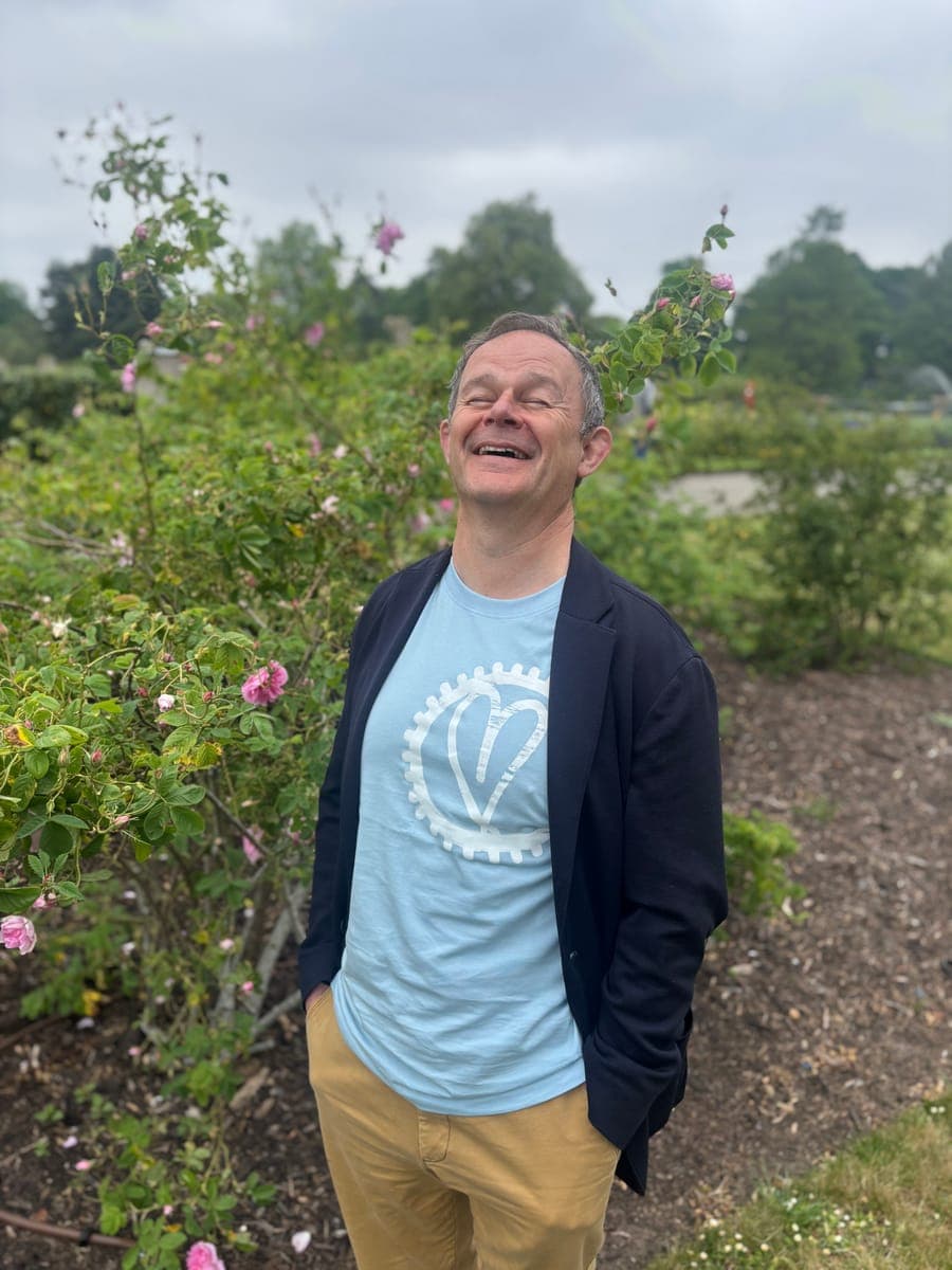 Andrew laughing in a rose garden