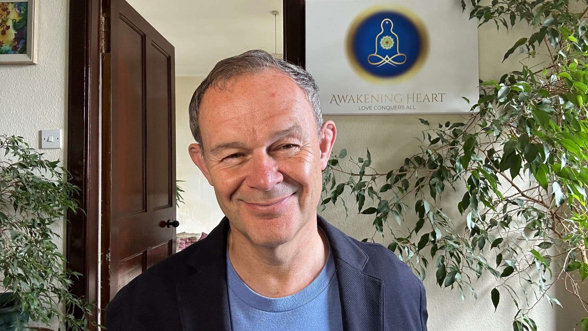 Andrew Cook, with the Awakening Heart logo behind him